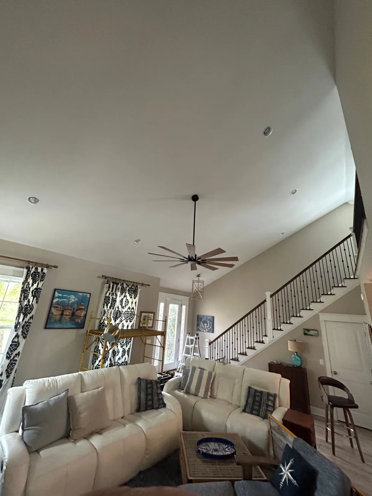 Before: Vaulted great room ceiling covered in natural wood planks with recessed lights and ceiling fan