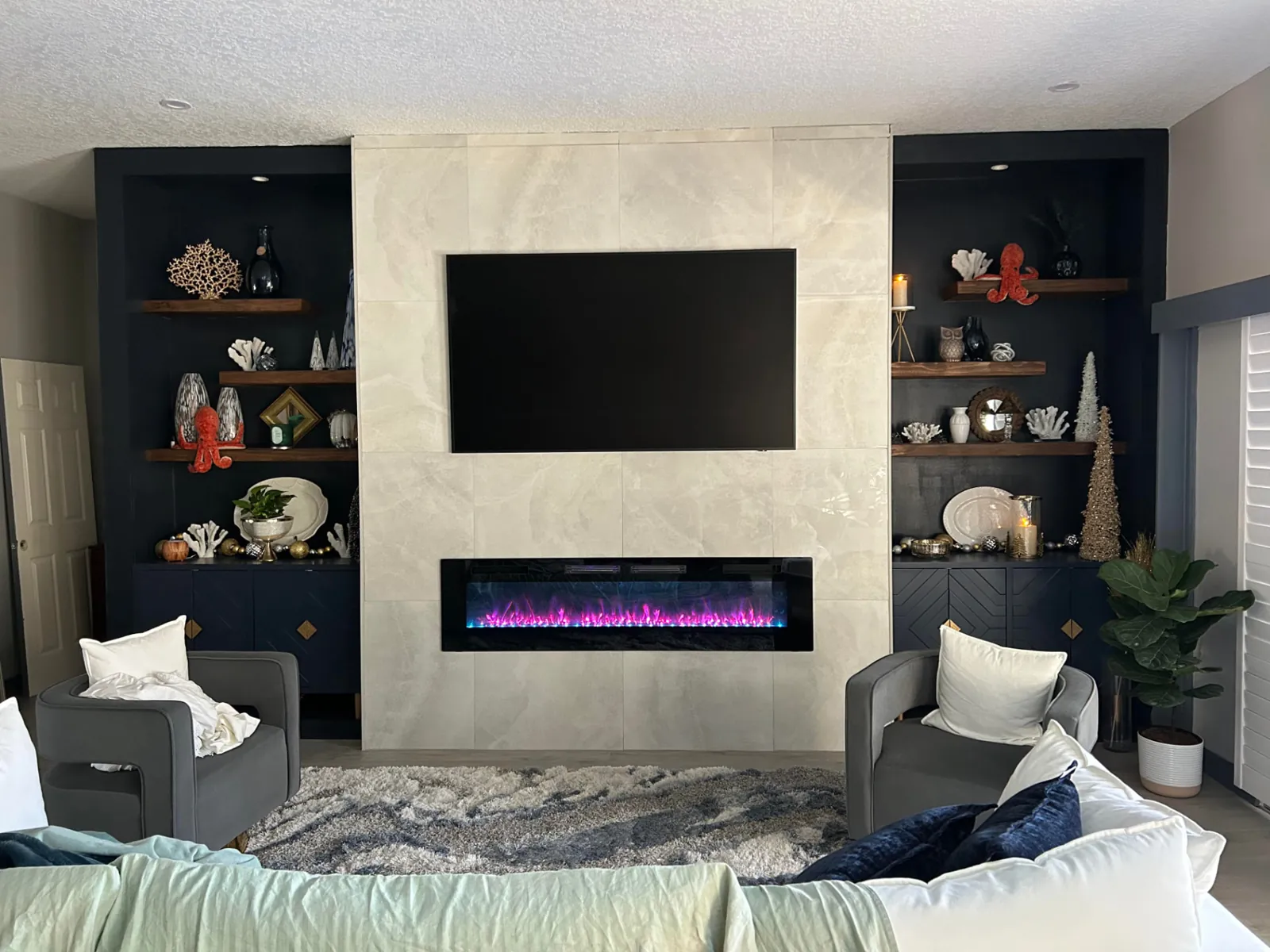 Finished: Living room feature wall with marble-look tile, linear fireplace and navy shelving niches