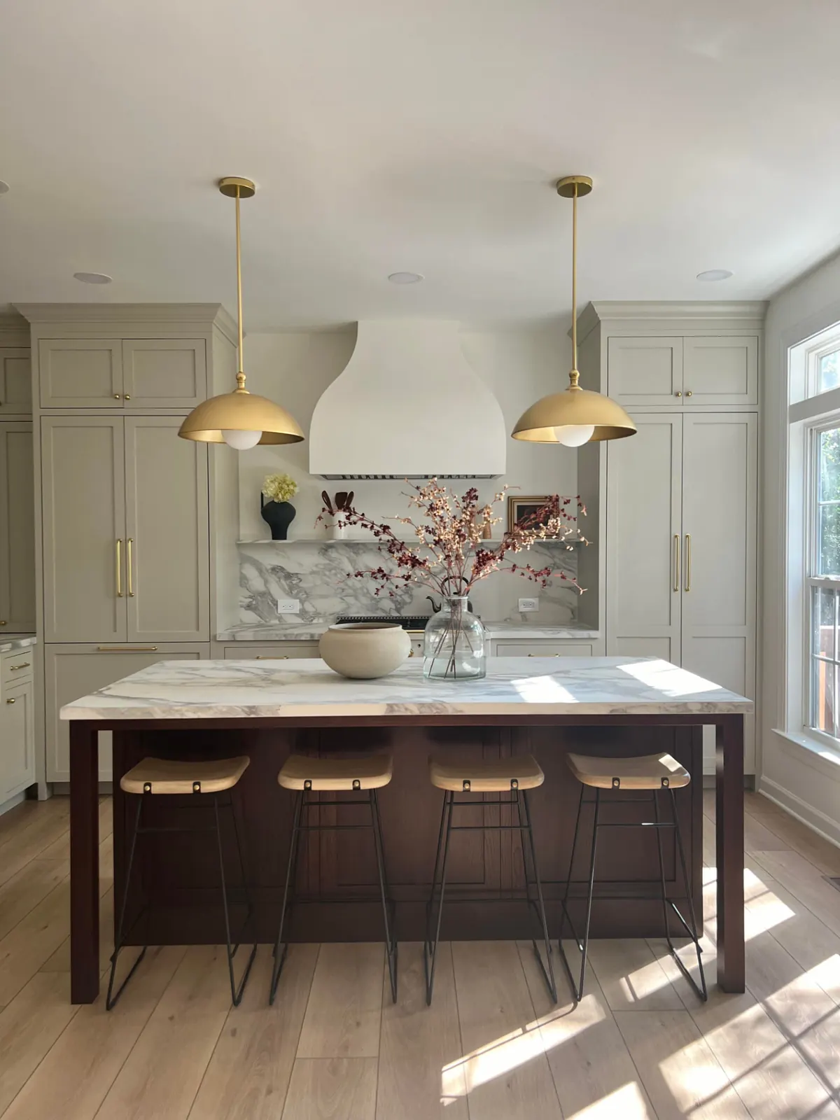 Renown kitchen remodel with greige cabinetry, a dark-stained island, marble-look counters and brass pendants