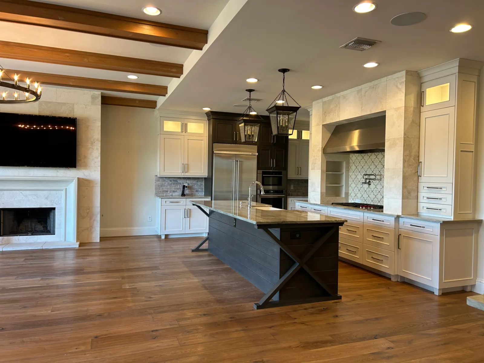 Renown whole-home renovation: open kitchen with plank island, beamed ceiling and fireplace living area