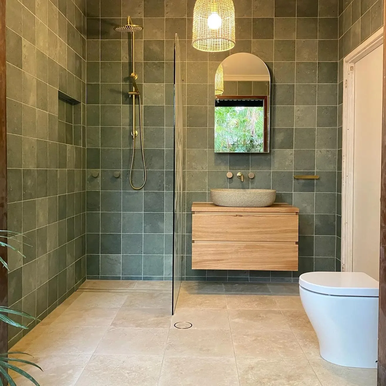 After: Sage-tiled bathroom with a curbless glass shower, floating timber vanity and stone vessel sink