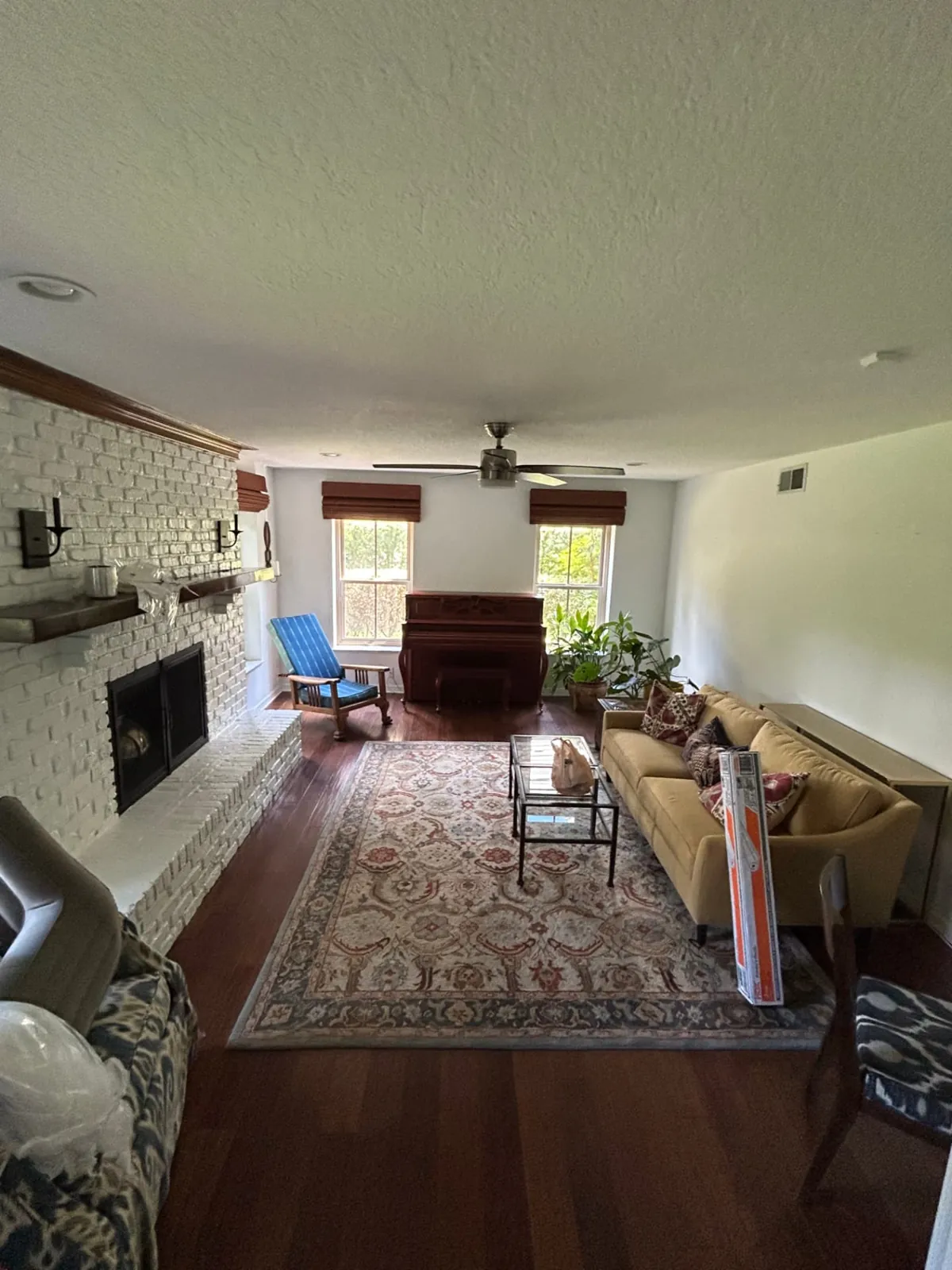 Before: Family room with a white brick fireplace and refinished light, natural wood floors