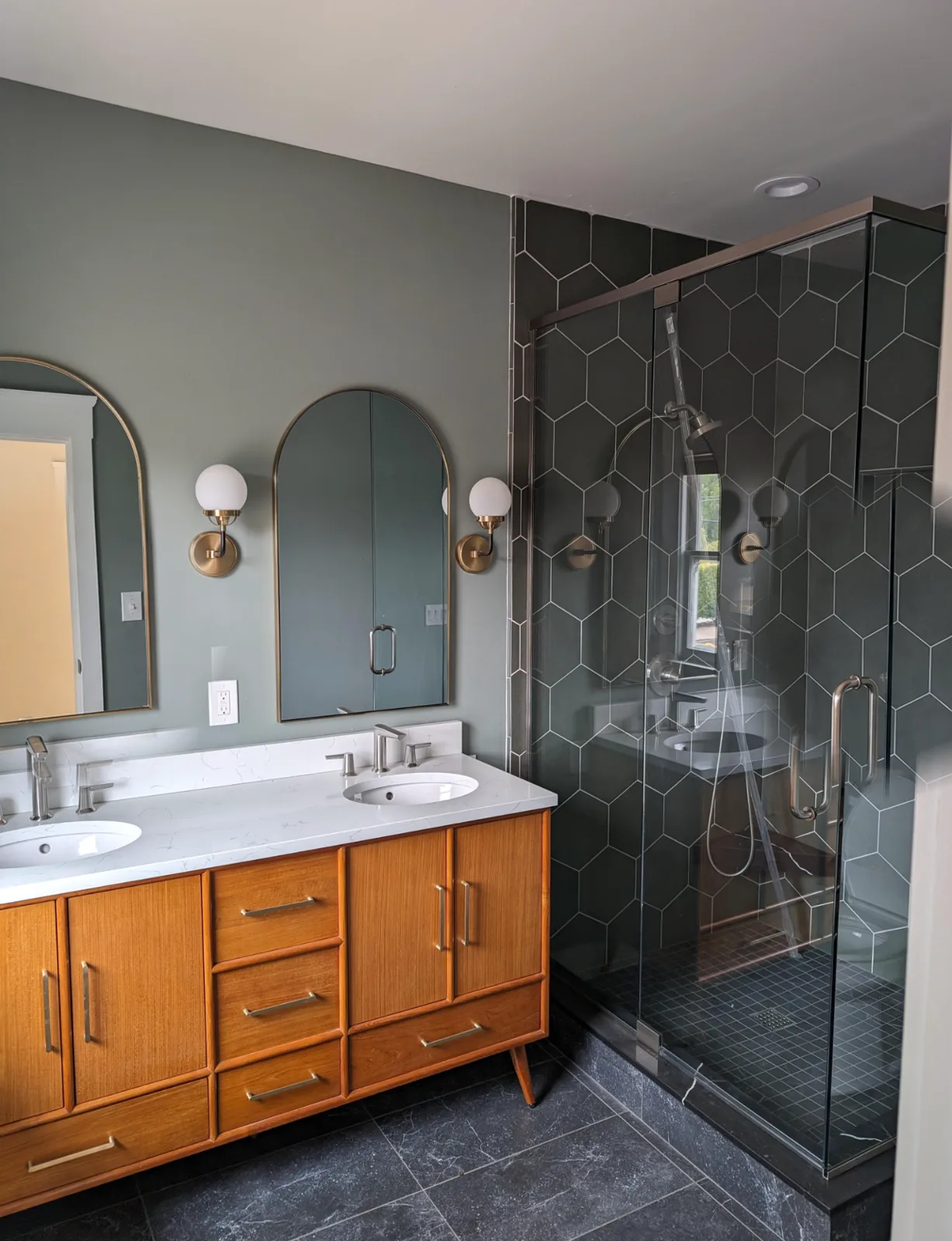 After: Craftsman-home bathroom with a dark hex-tile glass shower and mid-century wood double vanity